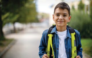 A young boy wearing a school backpack